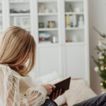 Girl Sitting on Sofa and Reading Book during Christmas - Caring for Your Mental Health During the Holidays