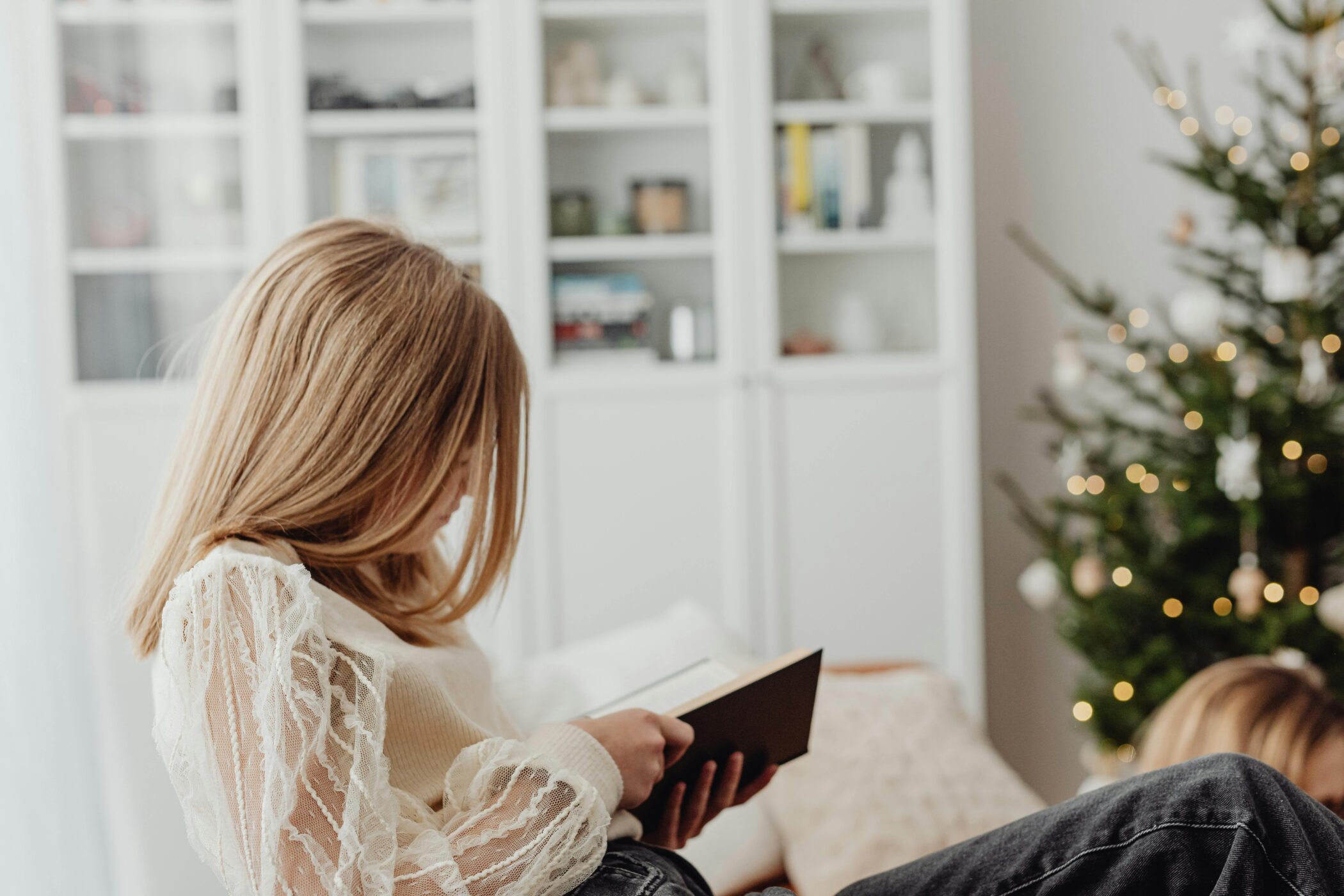 Girl Sitting on Sofa and Reading Book during Christmas - Caring for Your Mental Health During the Holidays