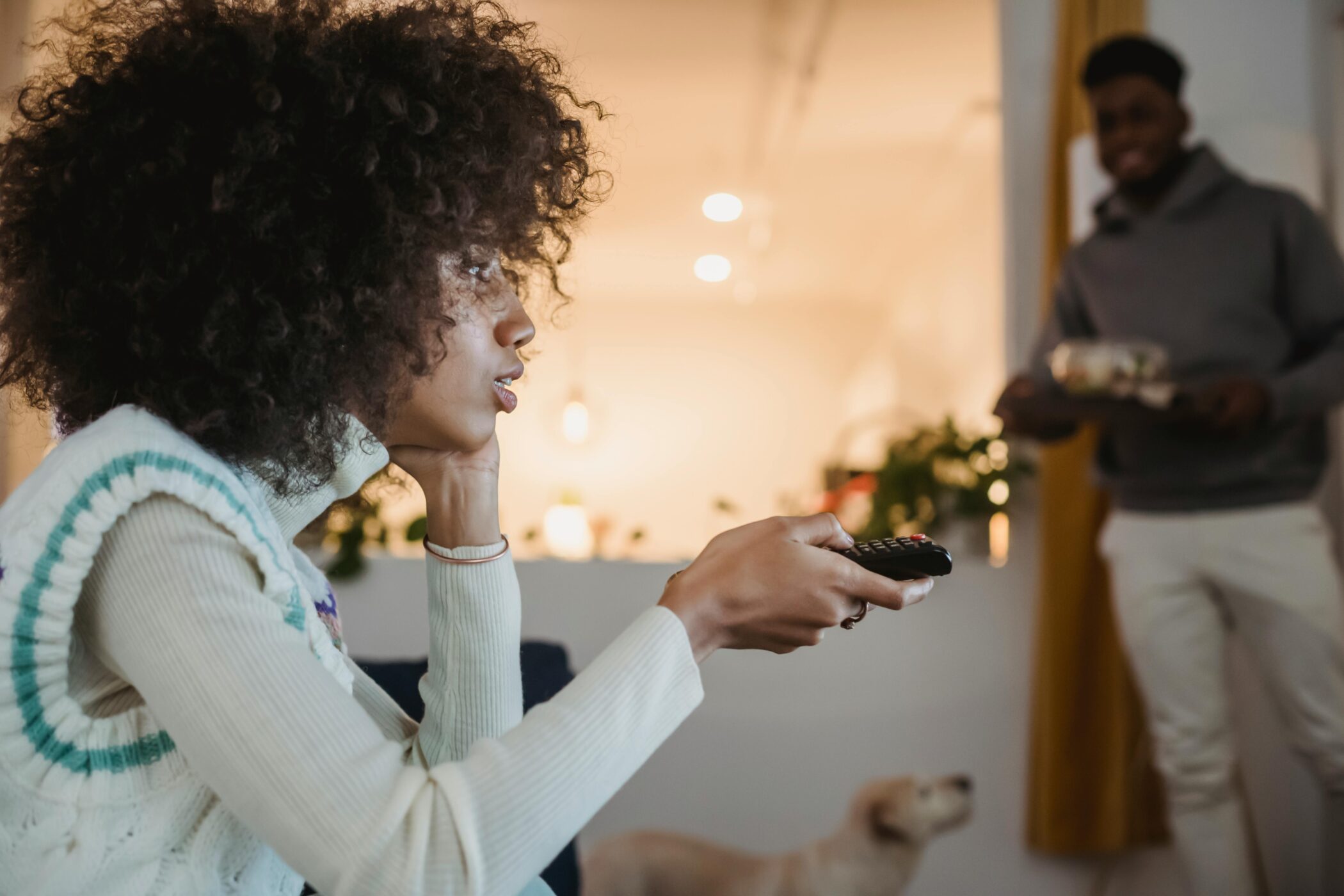 5 Mental Health Tips for Dealing With Political Stress - Woman watching tv with remote in hand.